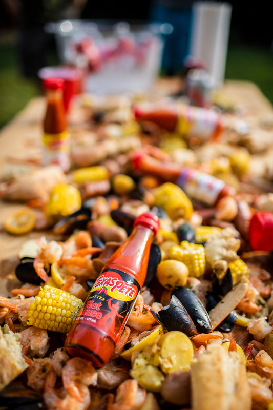 Assorted snacks and a bottle of Texas Pete hotter hot sauce on a table outdoors