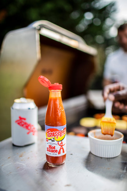 6oz Bottle of Texas Pete sauteed garlic hot sauce on a metal surface with a blurred background